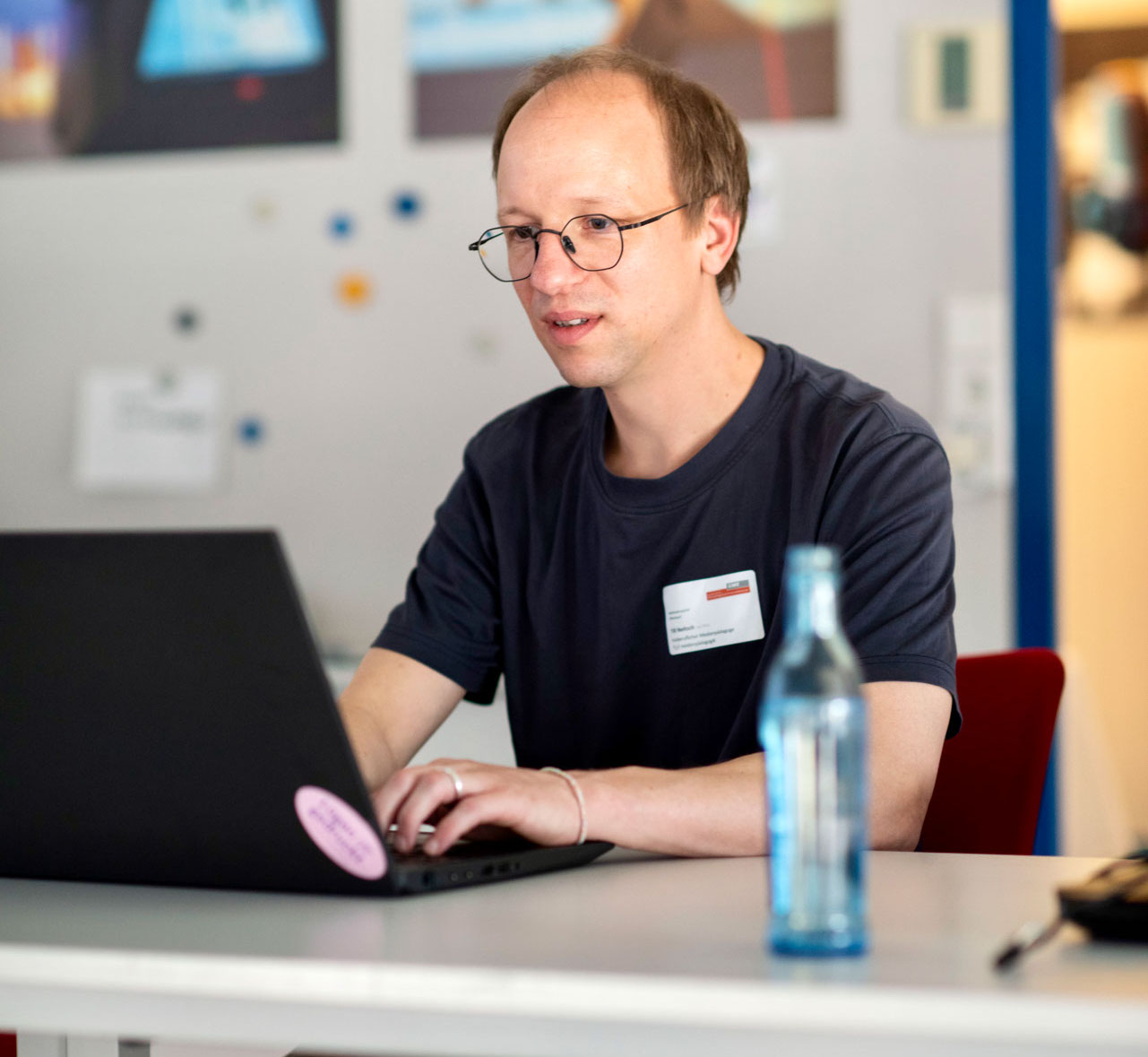 Till Neitsch, kurze blonde Haare und Brille, im T-Shirt, am Laptop während eines Workshops